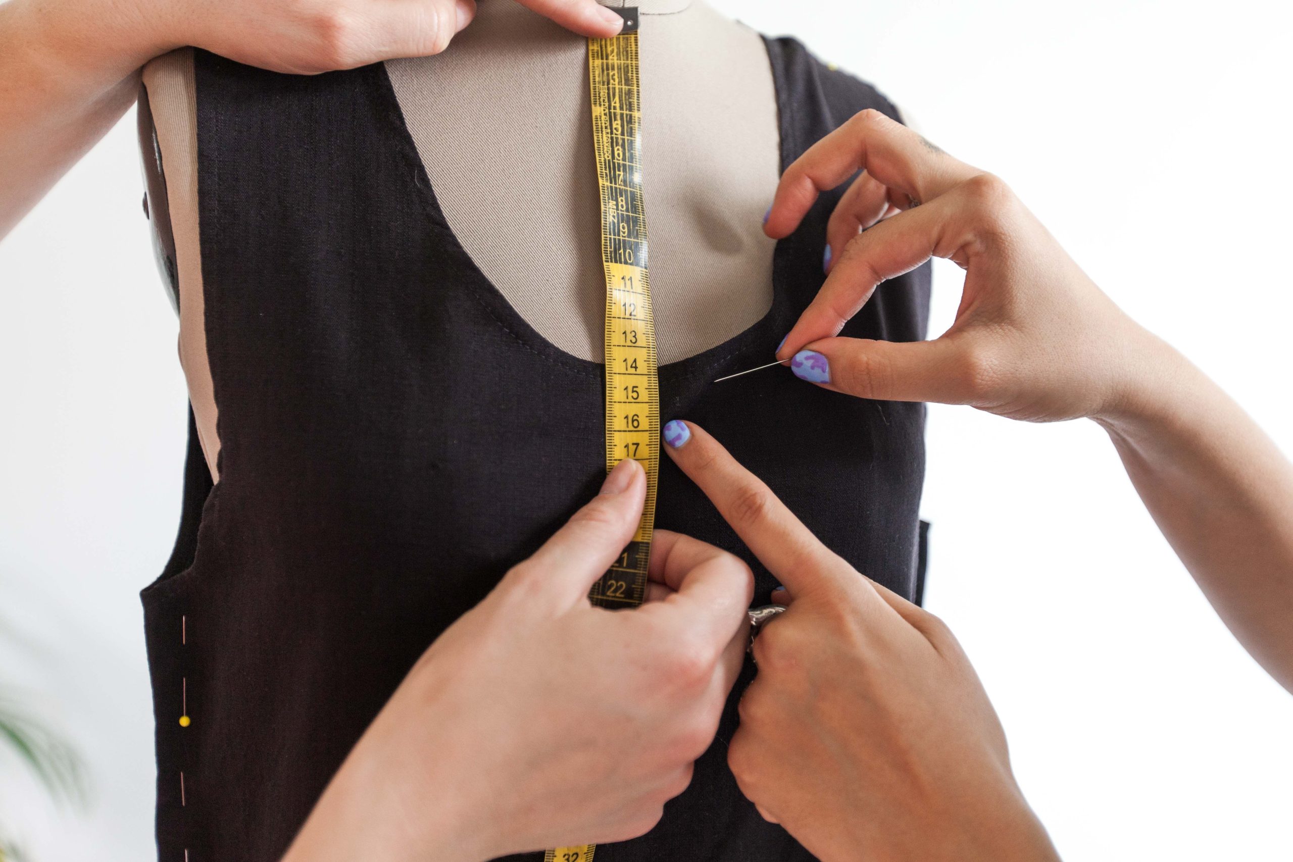 Mains mesurant une robe sur mannequin