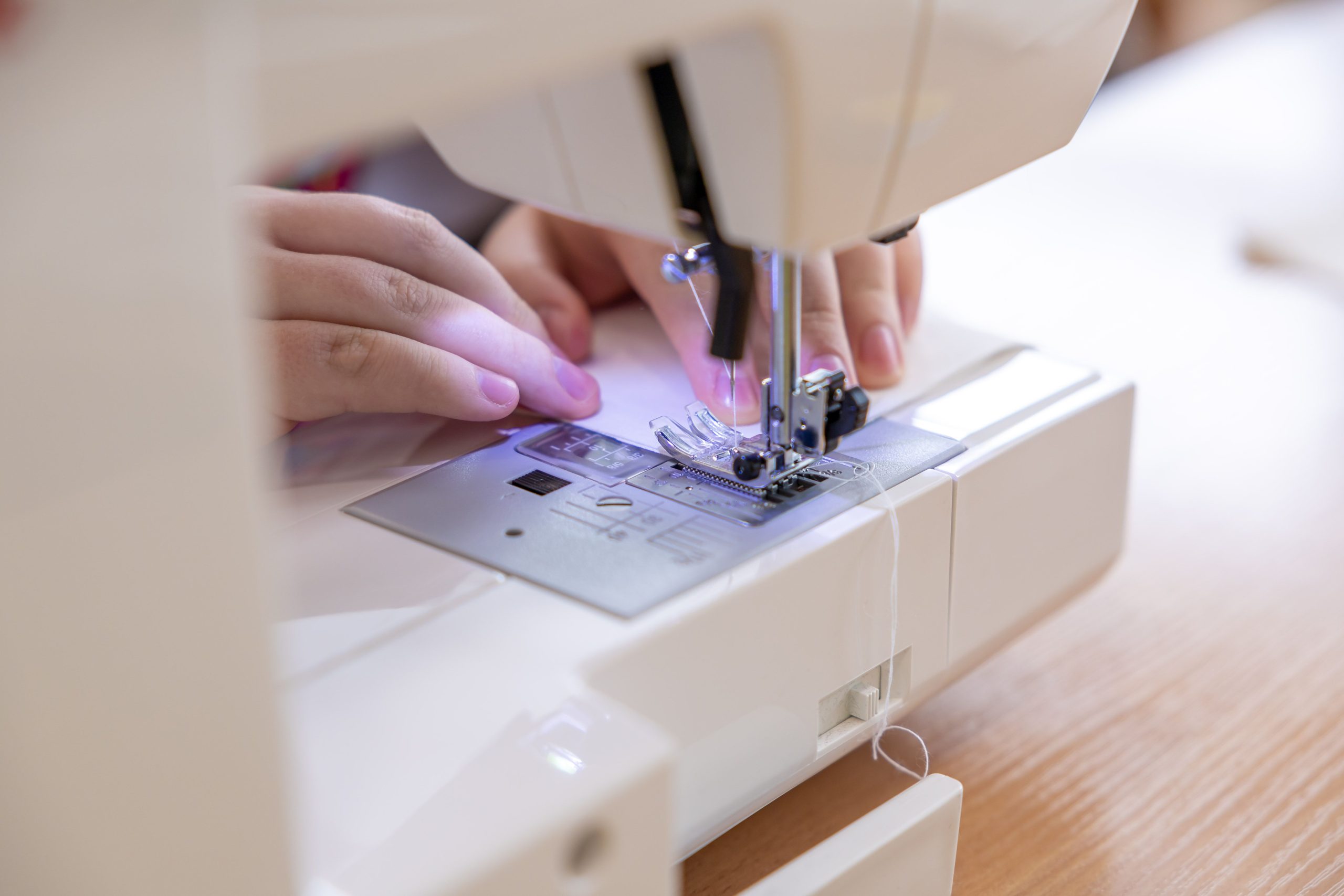 Mains guidant le tissu sur machine à coudre