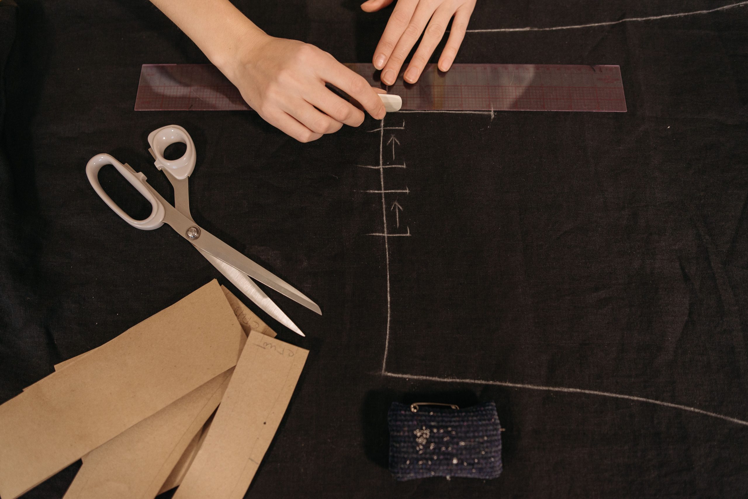 Mains marquant le tissu avec ciseaux et règle