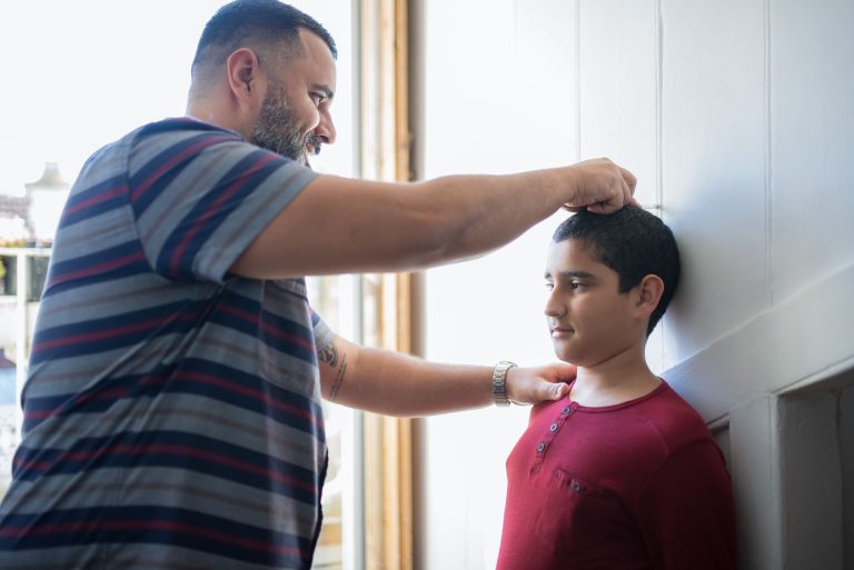 Père mesurant la stature de son fils contre un mur