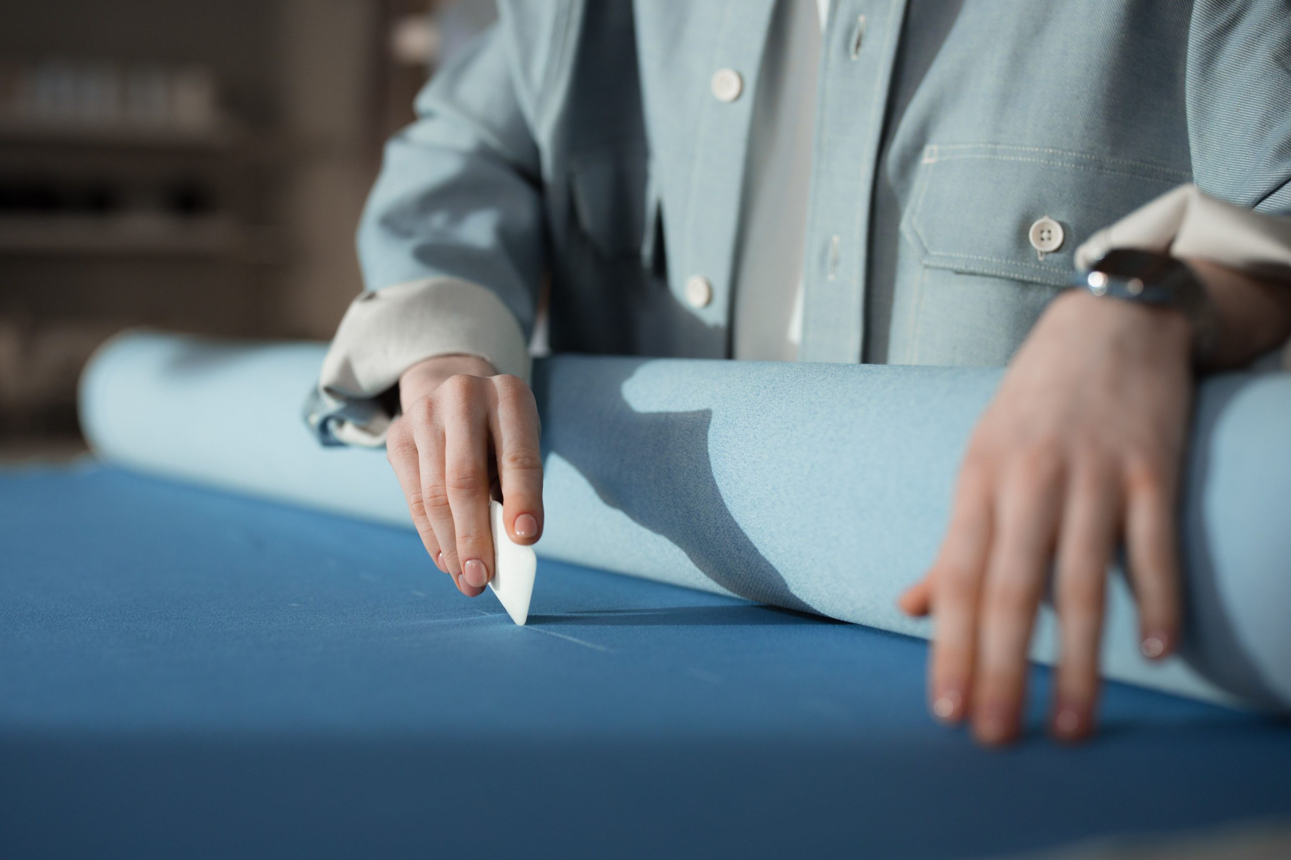 Mains de couturière marquant le tissu bleu à la craie