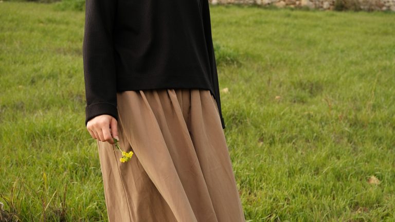 Femme en jupe soleil fluide tenant des fleurs sauvages