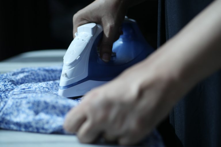 Gros plan des mains repassant tissu bleu