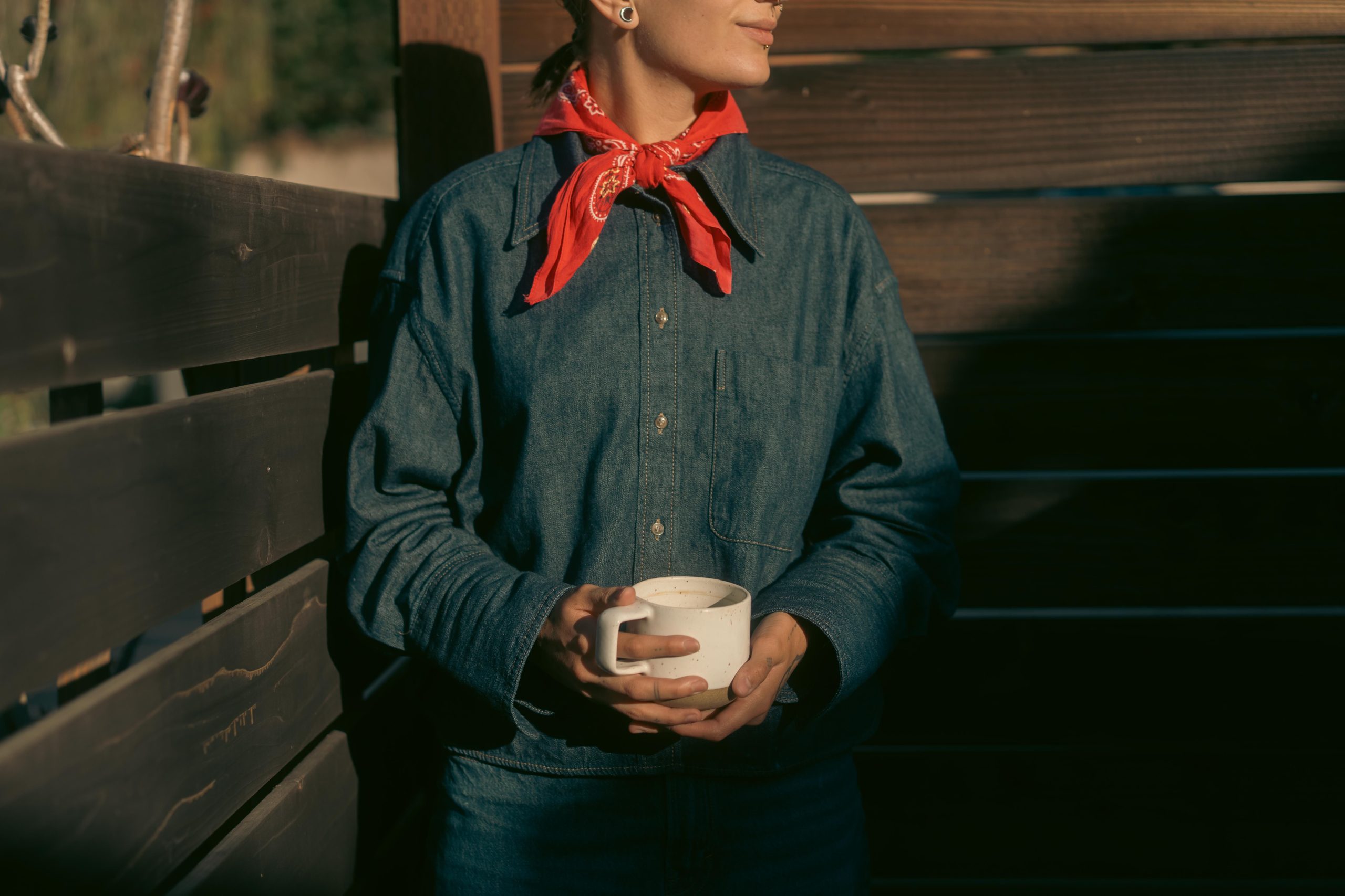 Femme en chemise en jean tenant café avec bandana rouge
