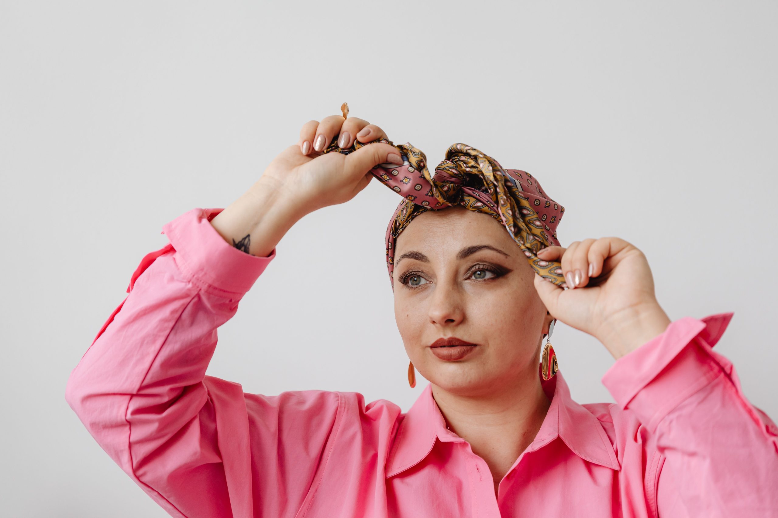 Femme en rose ajustant son foulard en studio