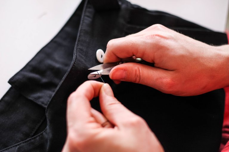Mains cousant tissu noir avec ciseaux de précision