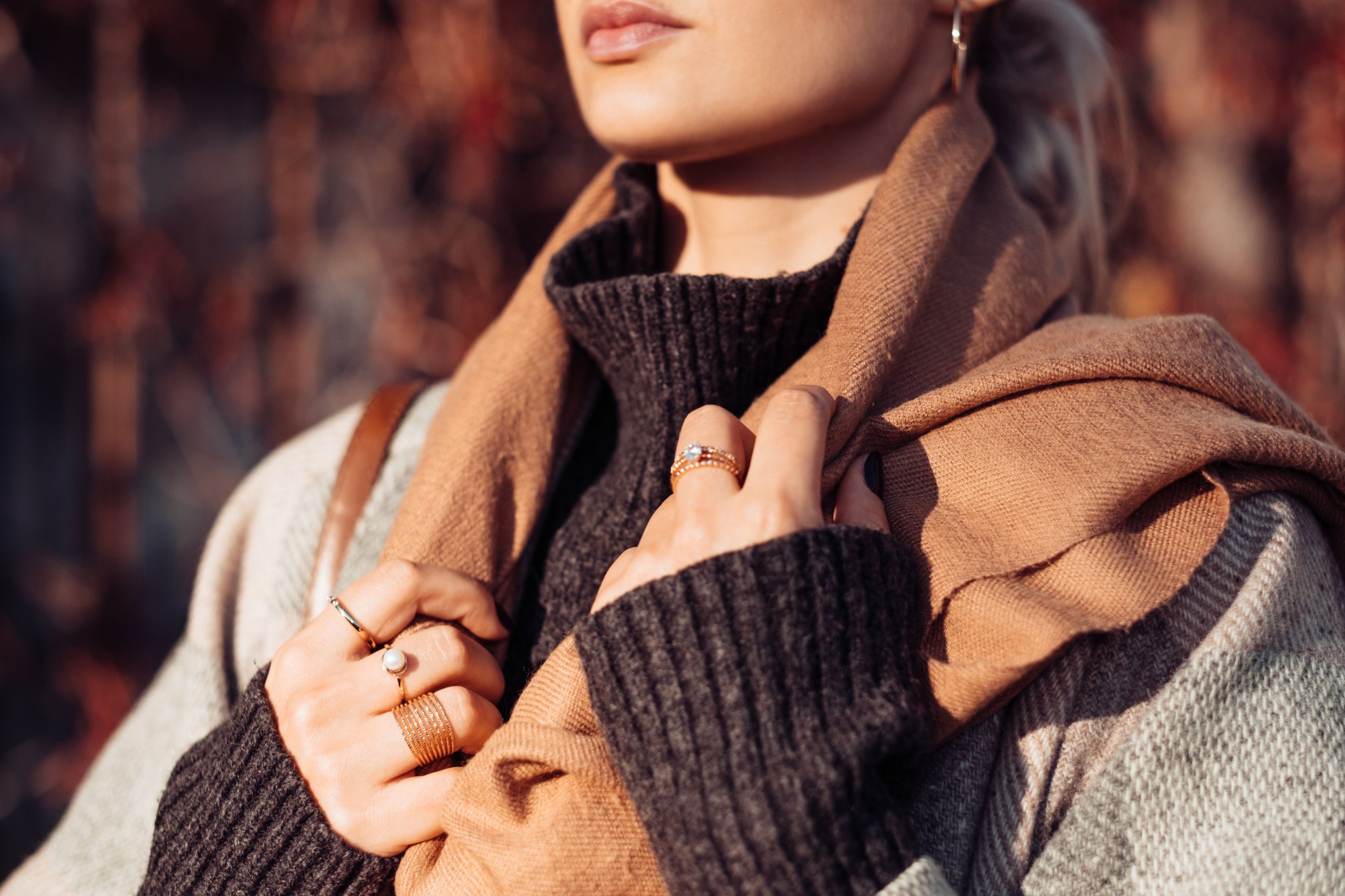 Femme portant un foulard marron tricoté et bagues dorées