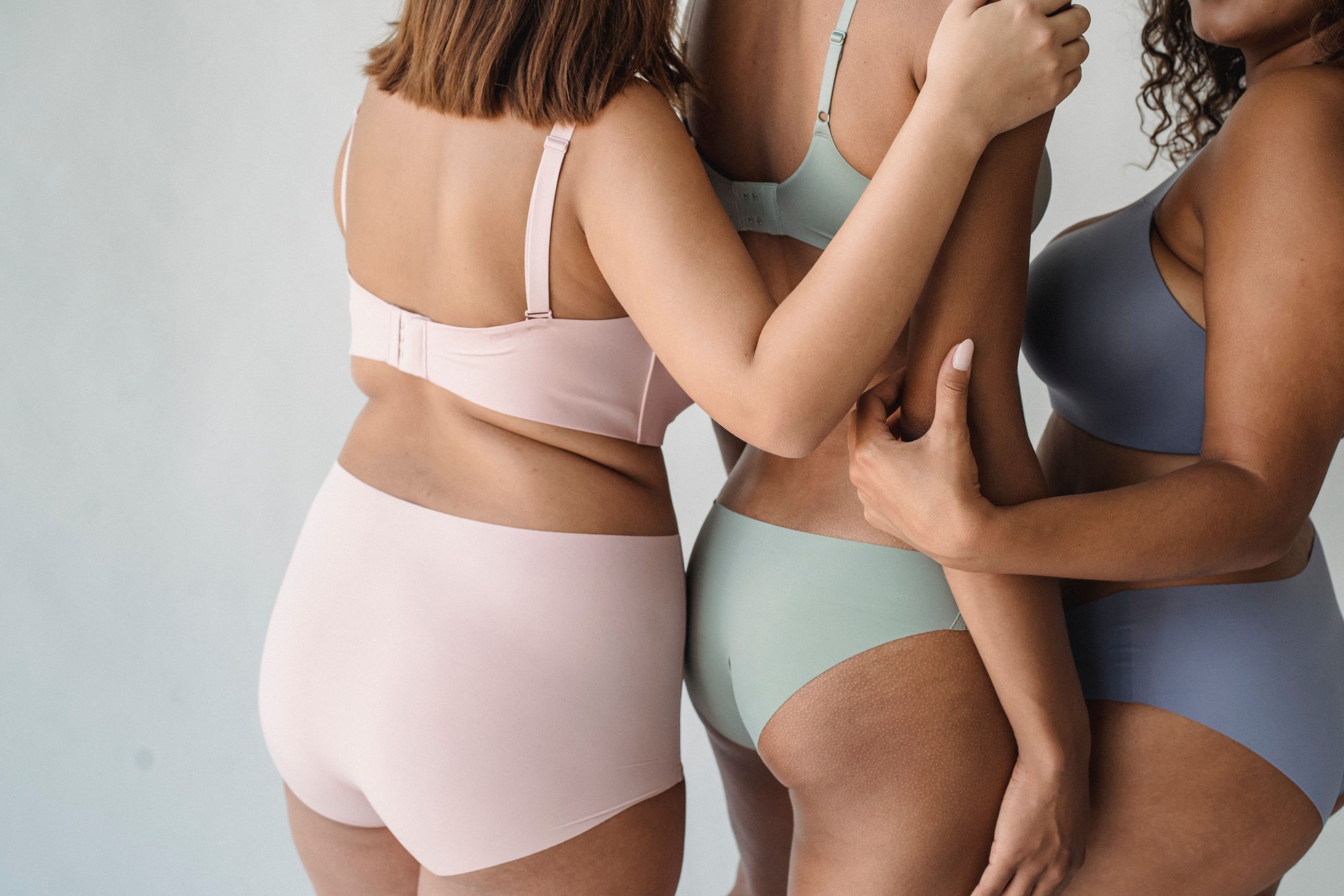 Trois femmes en lingerie colorée s'étreignent