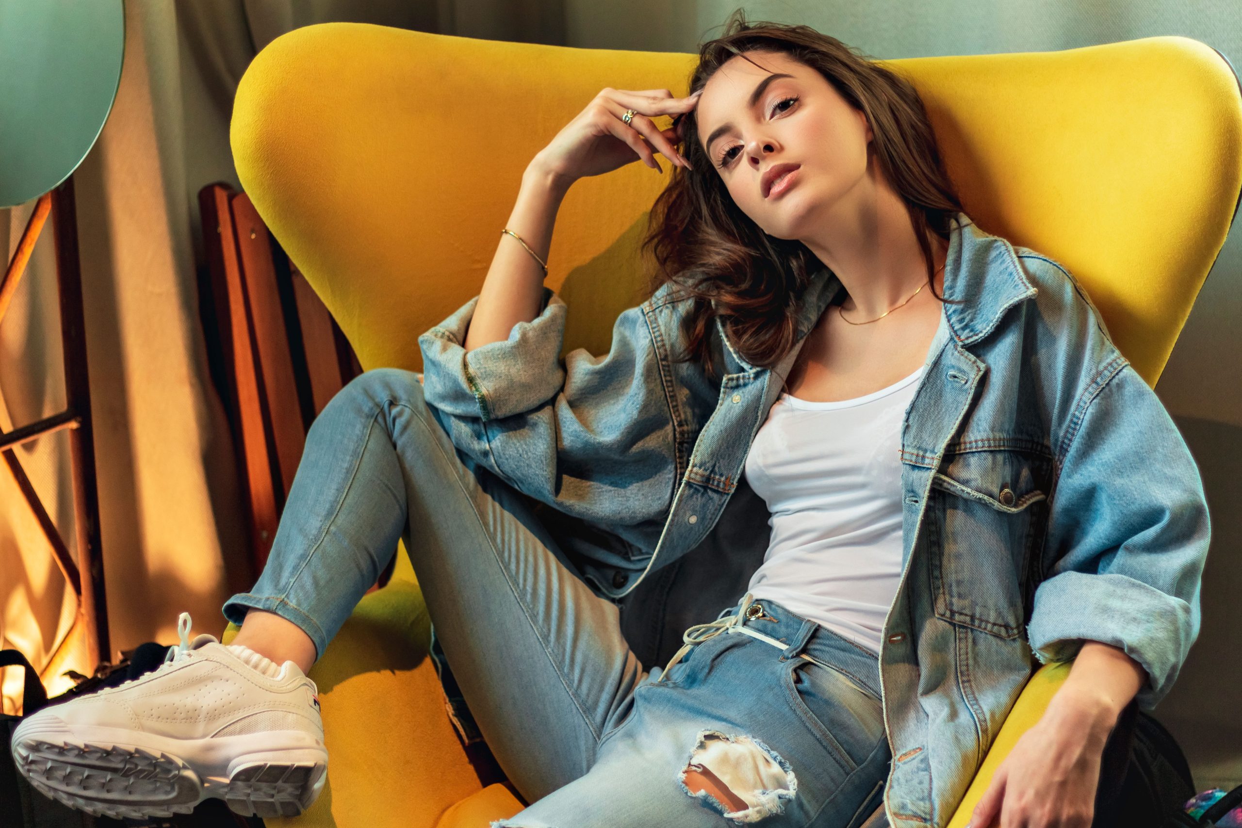 Femme stylée en denim sur chaise jaune