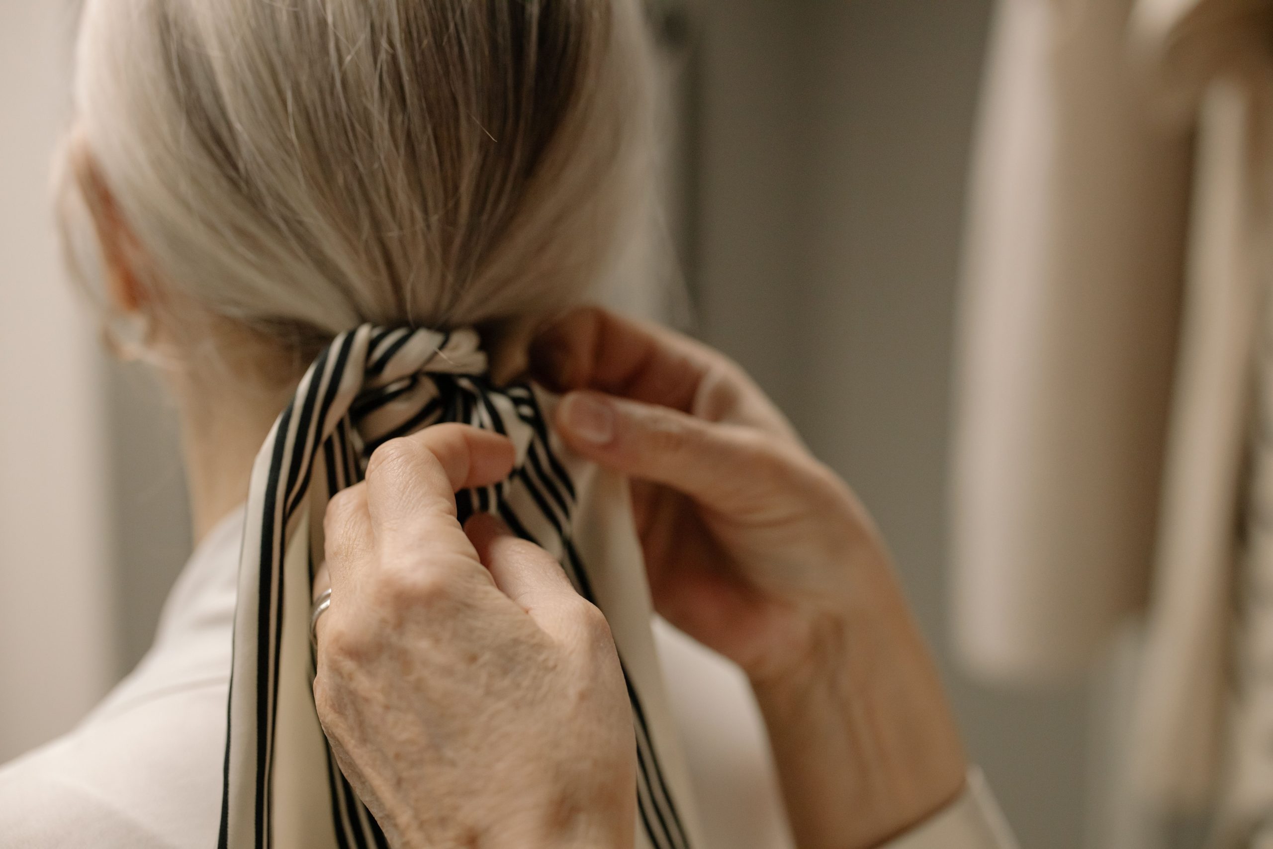 Mains nouant un ruban rayé dans cheveux gris