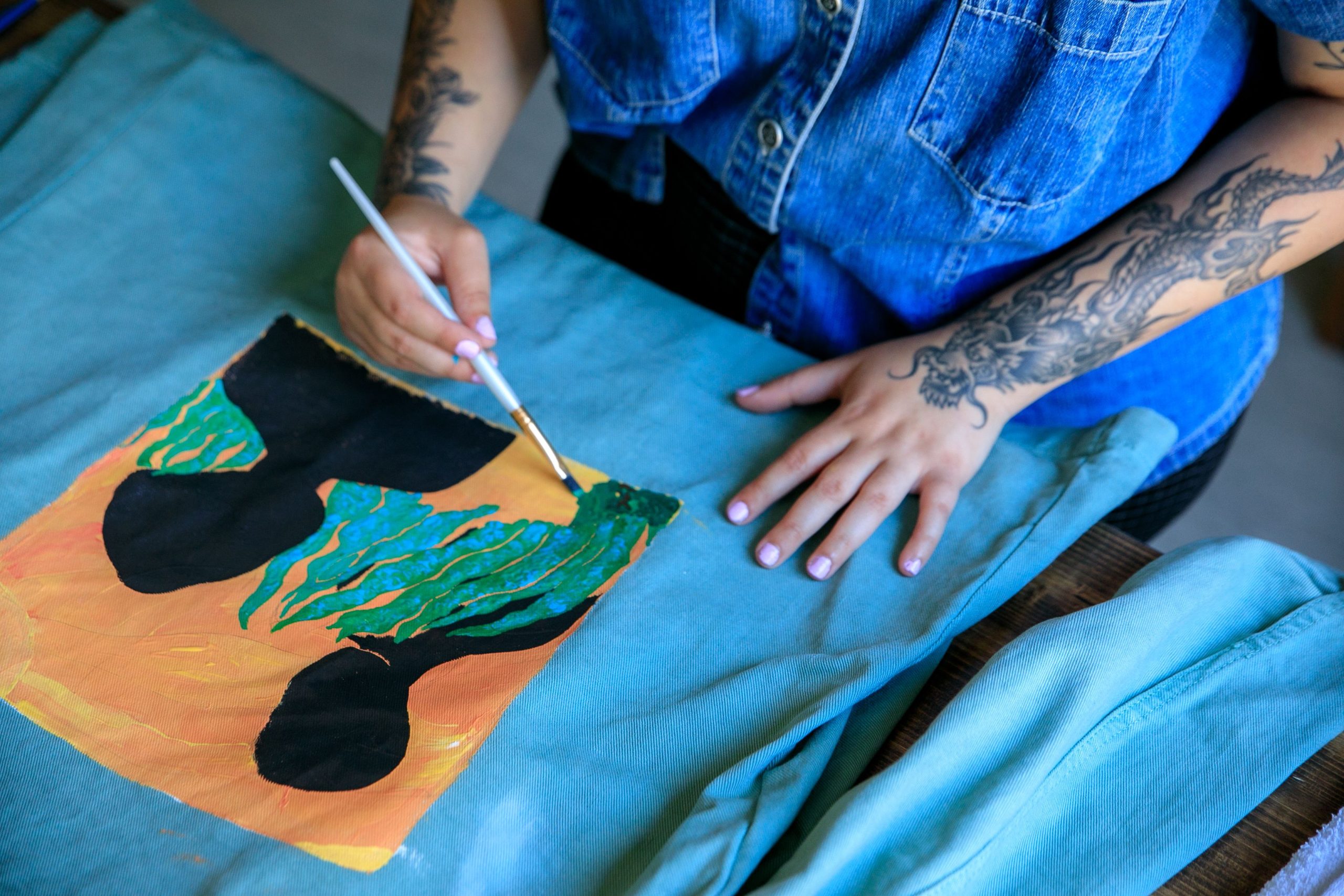 Femme peint un design coloré sur tissu
