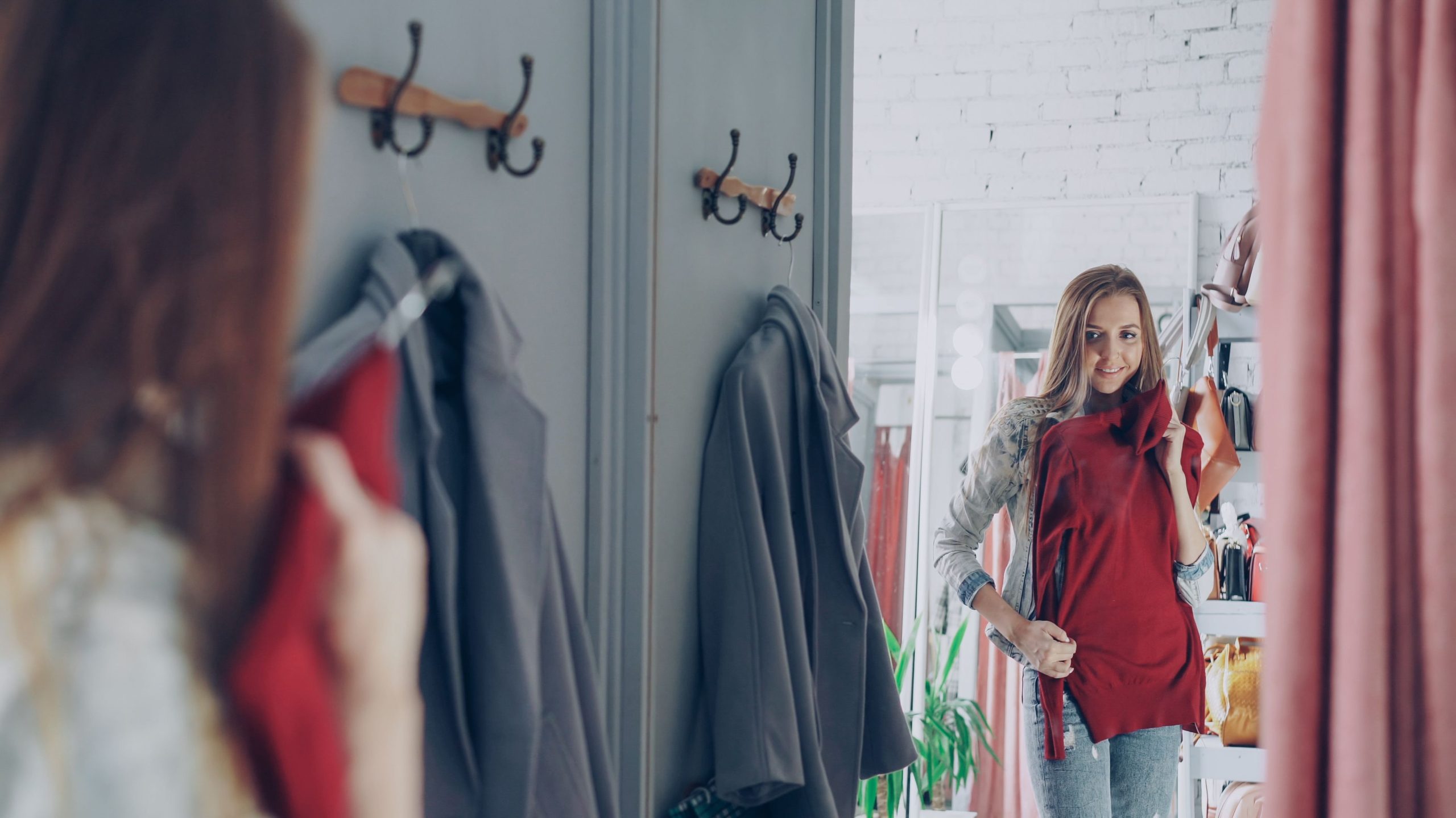 Femme souriante essaye une robe rouge