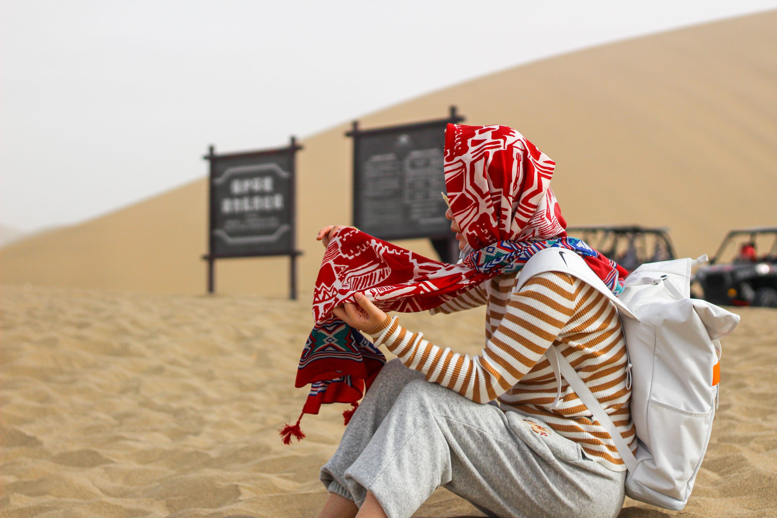 Voyageur avec foulard assis sur le sable du désert
