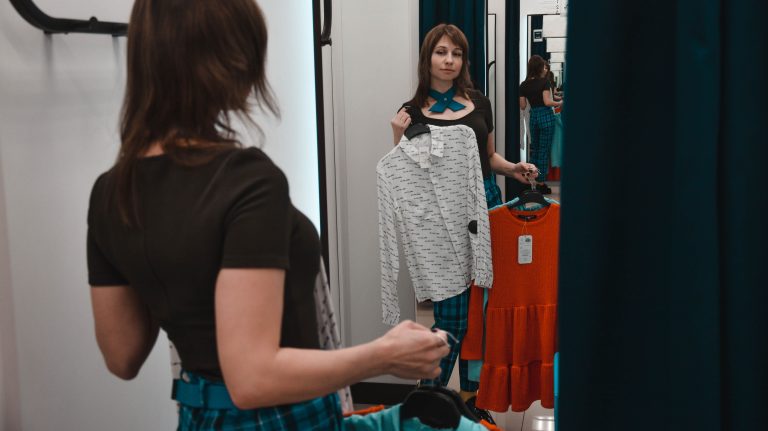 Jeune femme essayant des chemises en magasin