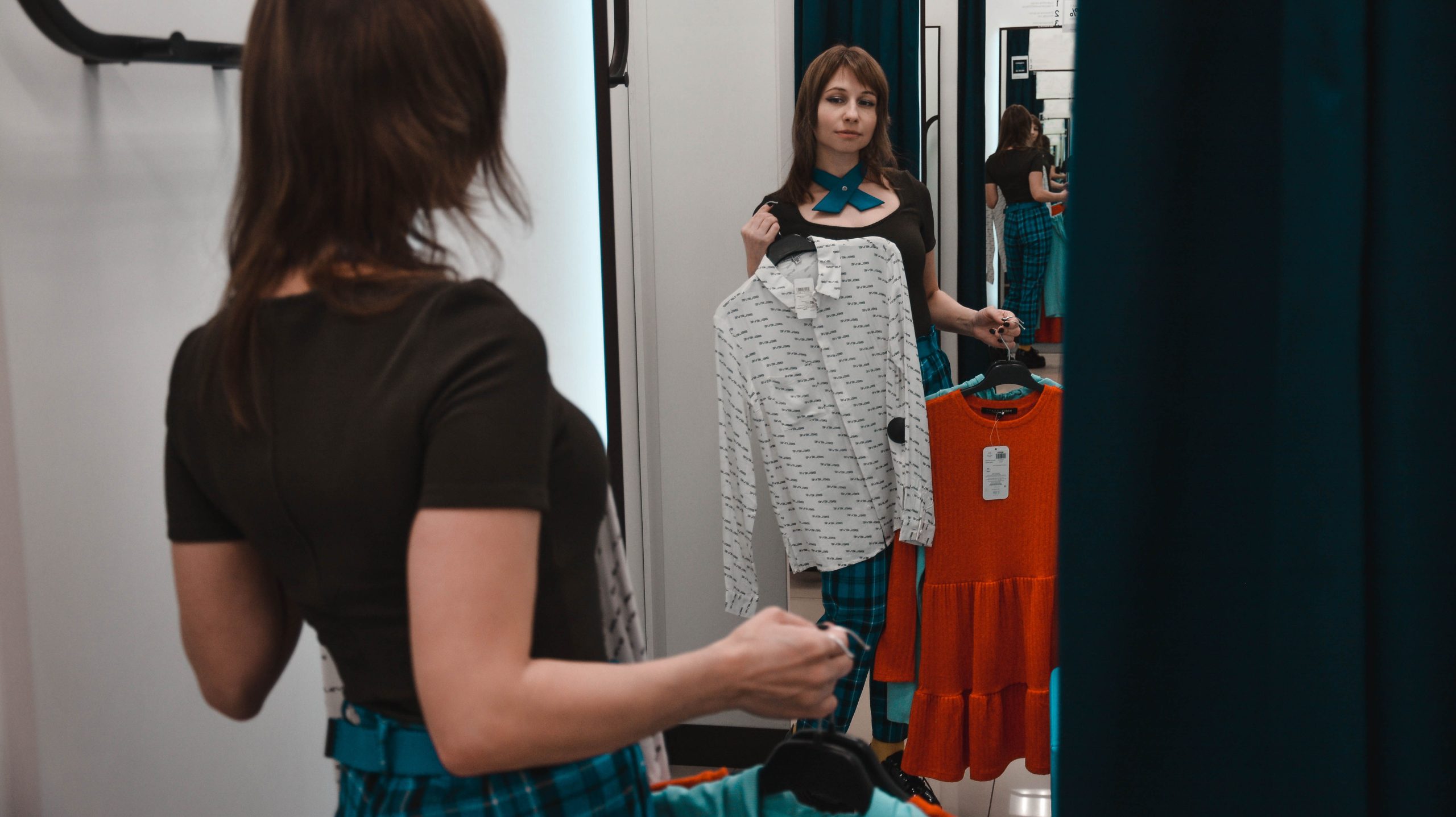 Jeune femme essayant des chemises en magasin