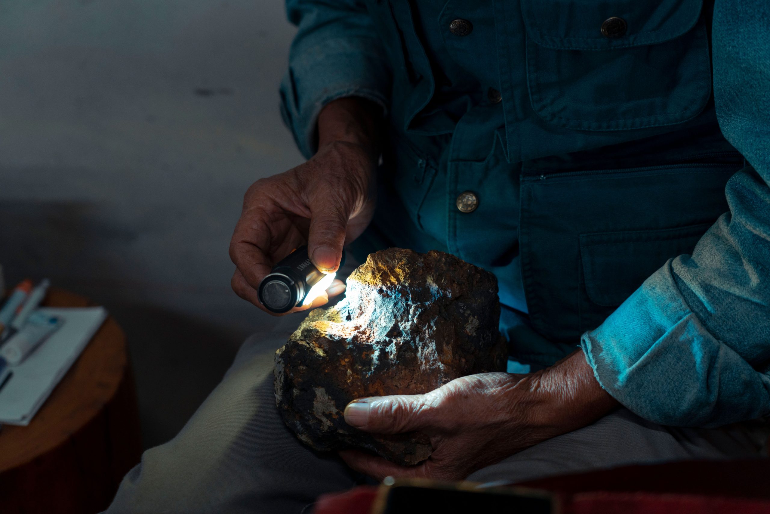 Mains examinant une pierre avec une lampe