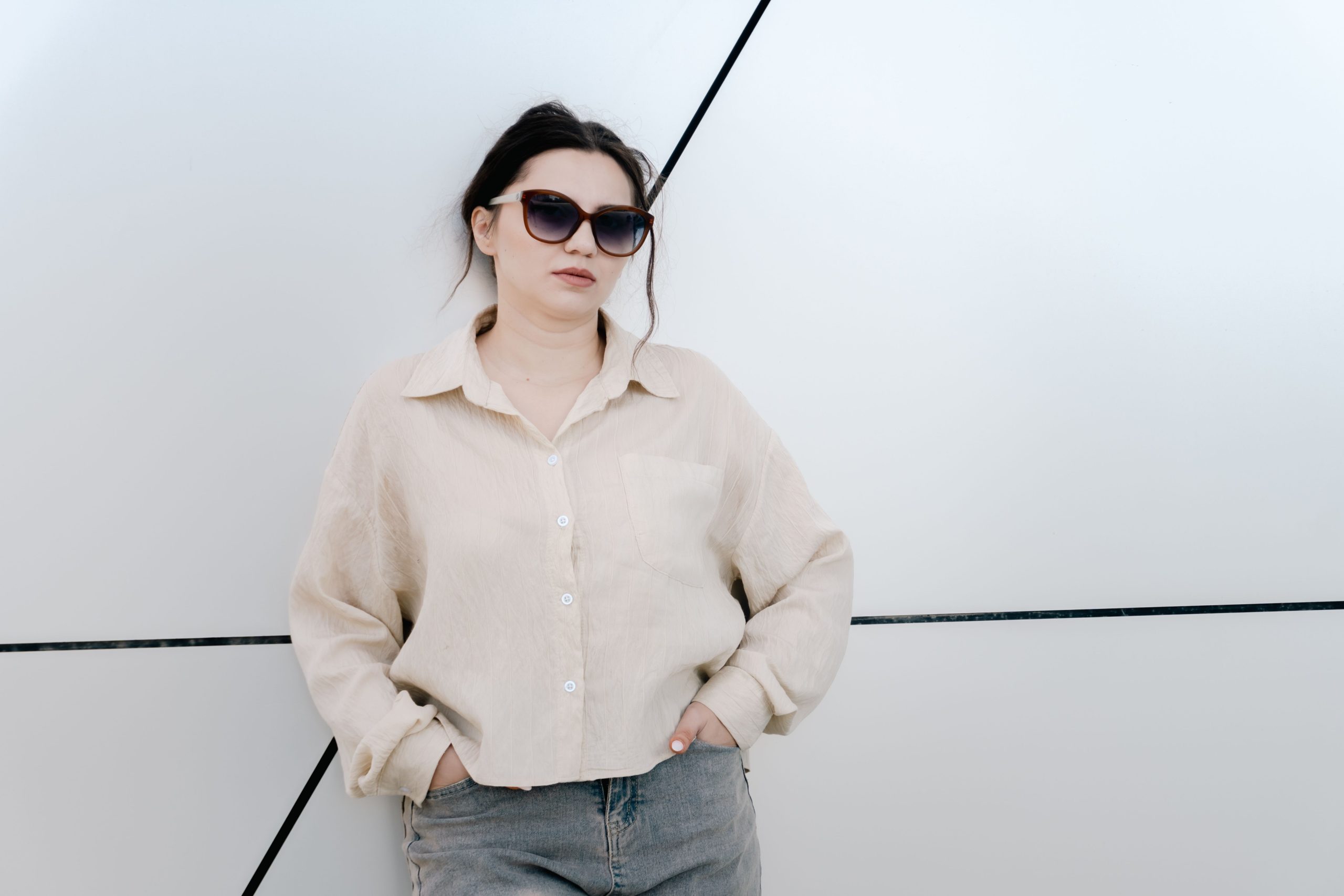 Femme tendance en lunettes de soleil contre mur geometrique