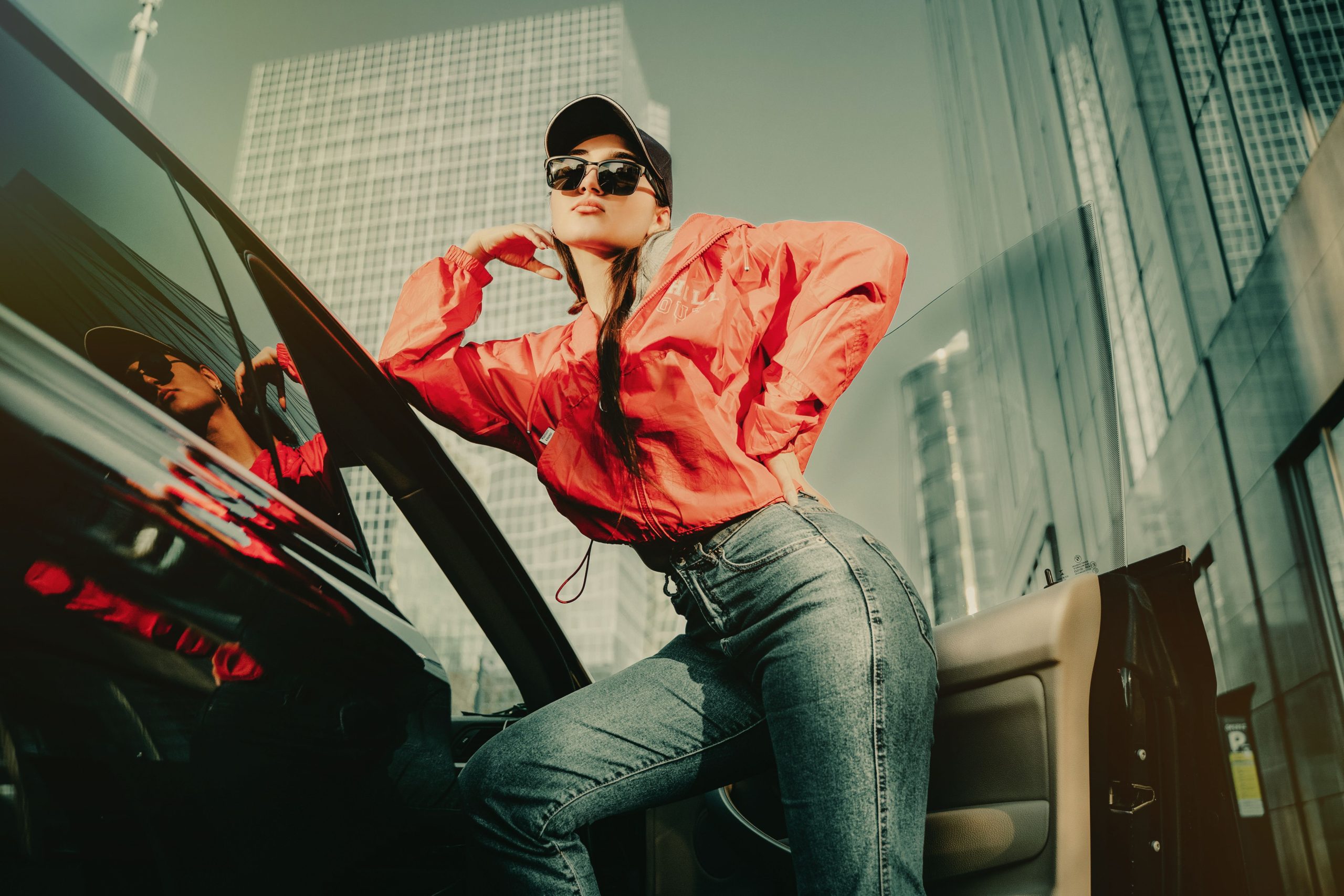 Femme en jean bootcut posant pres d'une voiture en ville