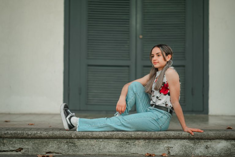 Jeune femme en jean bootcut et top fleuri assis dehors