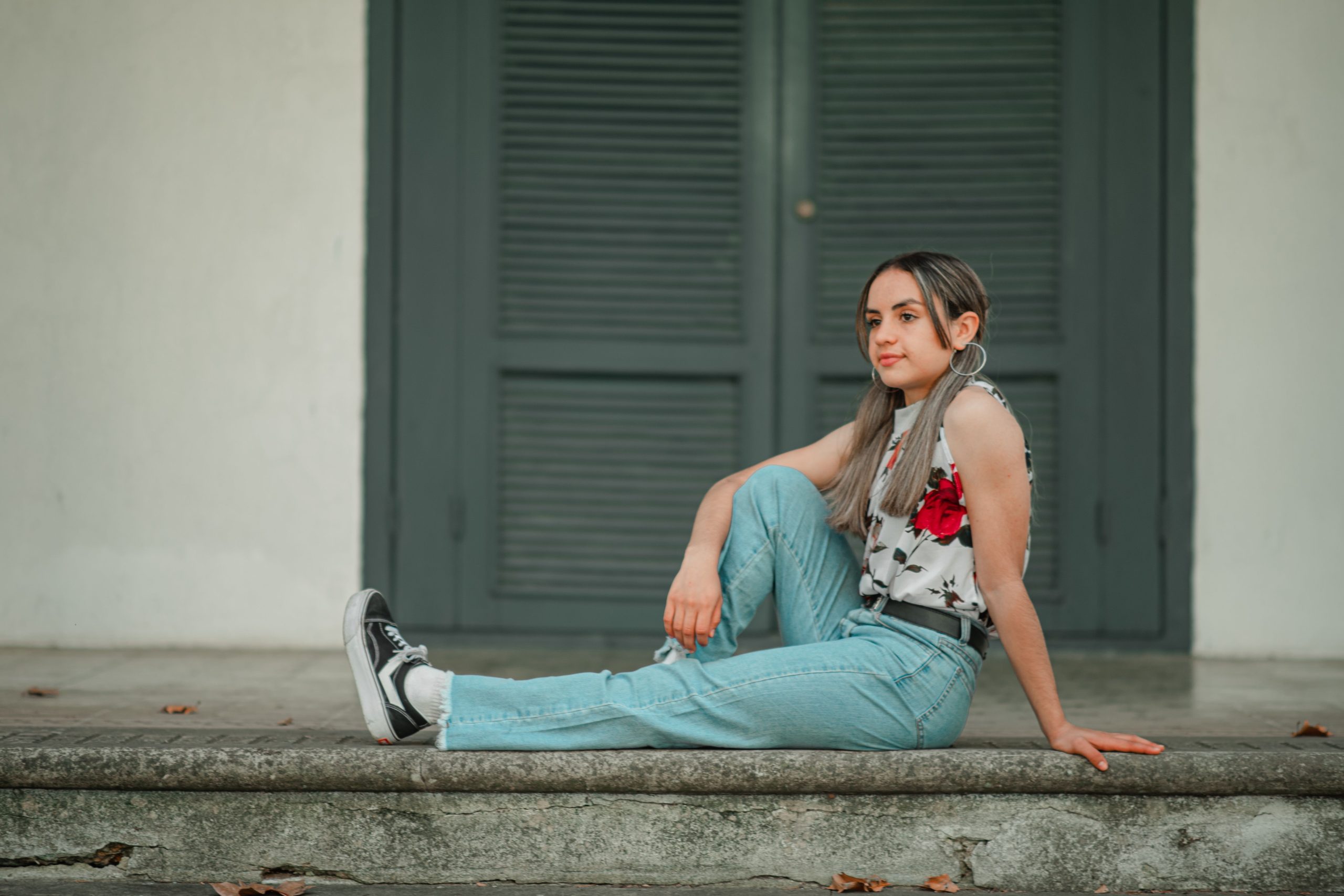 Jeune femme en jean bootcut et top fleuri assis dehors