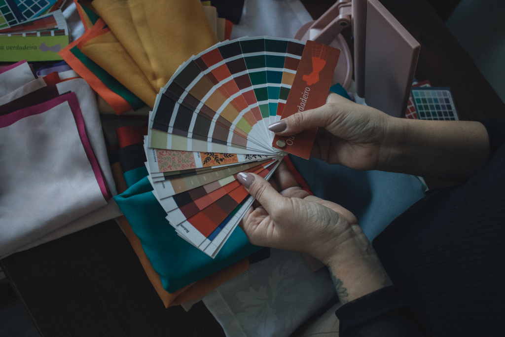 Mains tenant un nuancier au-dessus de tissus colorés