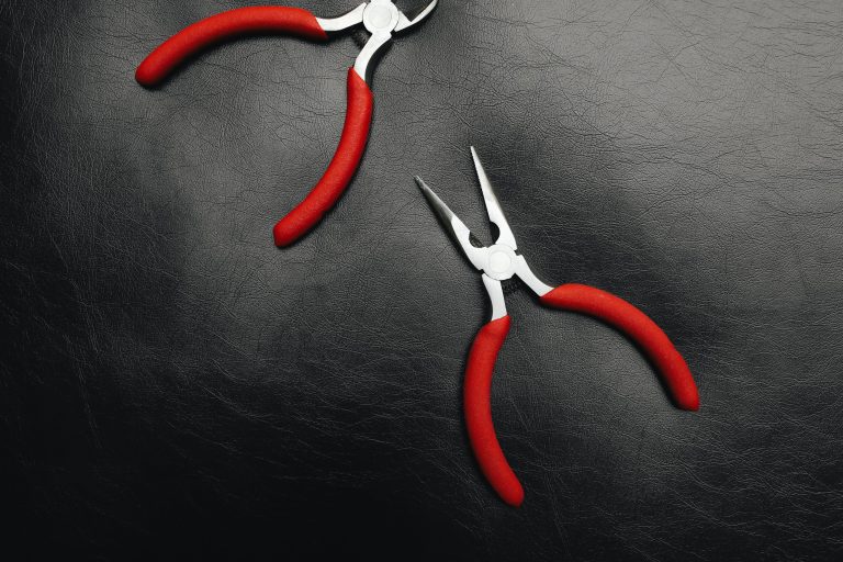 Deux pinces à poignées rouges sur cuir noir